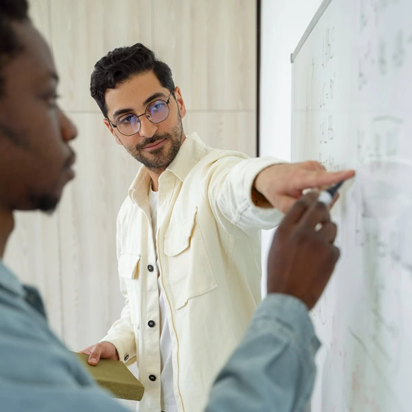 Two people working on a whiteboard together